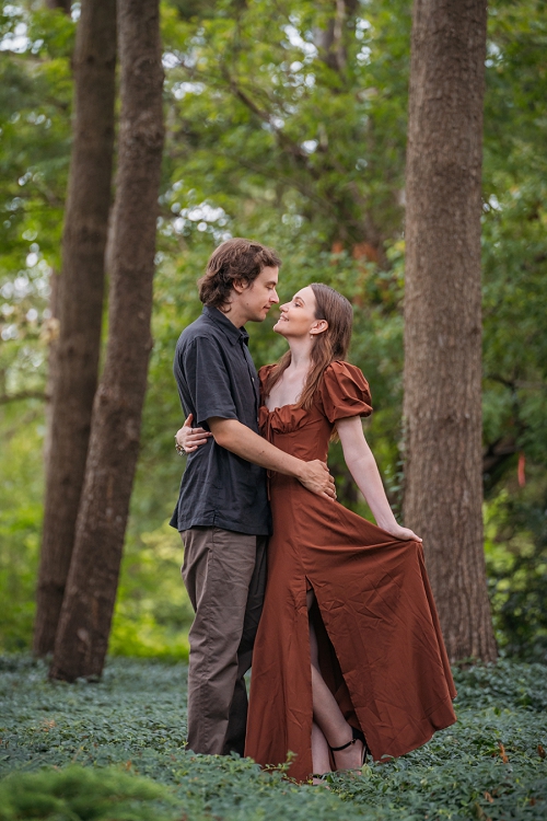  engagement portrait where she is holding her dress out and he is holding her