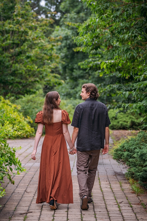 engagement photo from behind where couple is holding hands and looking at each other