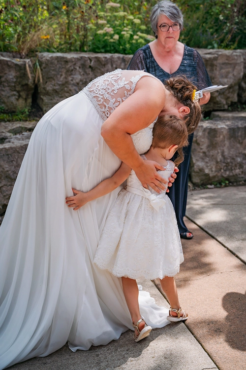 daughter hugging bride during wedding ceremony 