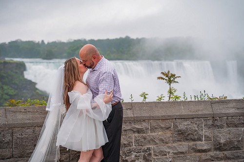 bride and groom kissing in front of niagara falls