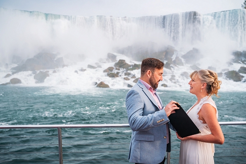 bride and groom reading vows on cruise with niagara falls 