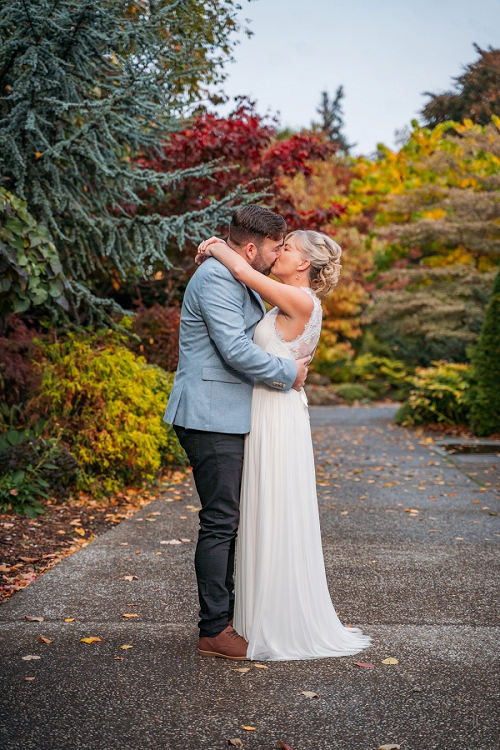  Bride and groom kissing with fall colours in background