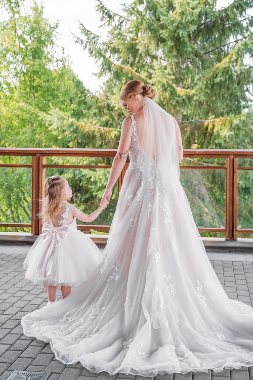 bride and flower girl holding hands and looking at each other