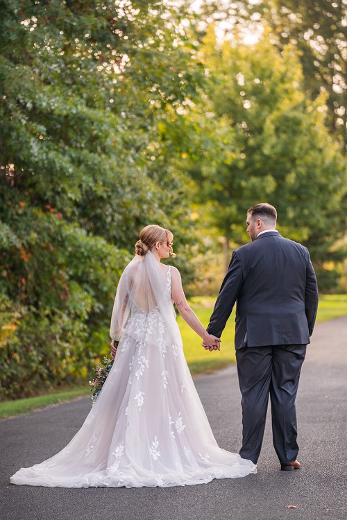 bride and groom holding hands from behind and walking