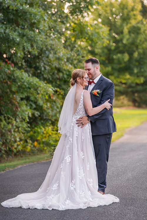 brides dress from behind while groom is holding her