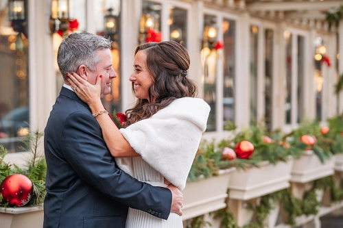  bride holding grooms face surrounded by christmas decorations in niagara on the lake