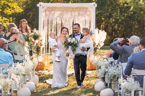 bride and groom walking down aisle with their kids 