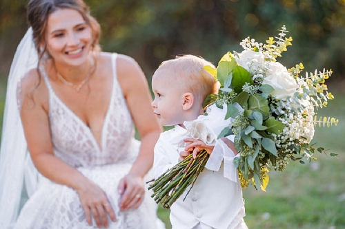 bride smiling at her son who is holding her bouquet of flowers 