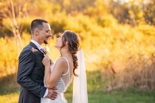 bride holding grooms jacket and smiling at him 