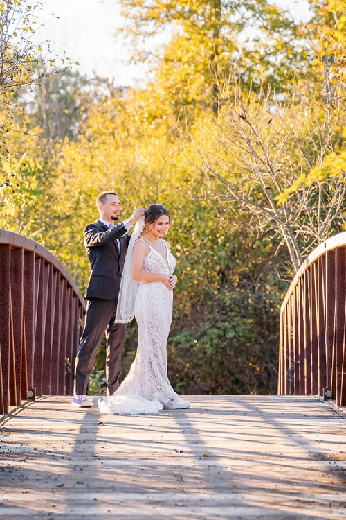 groom helping bride with her veil 