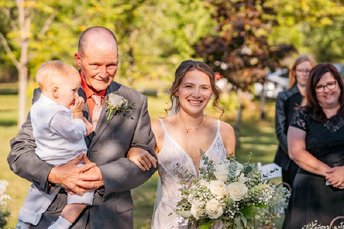 bride walking down aisle with her dad and son 