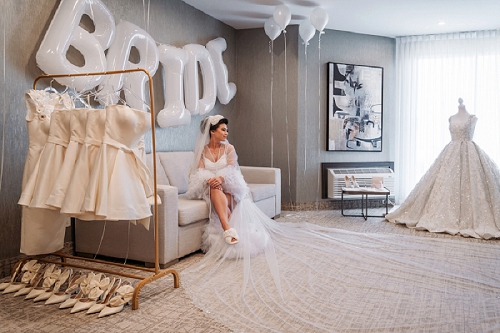 bride sitting with wedding dress on display 